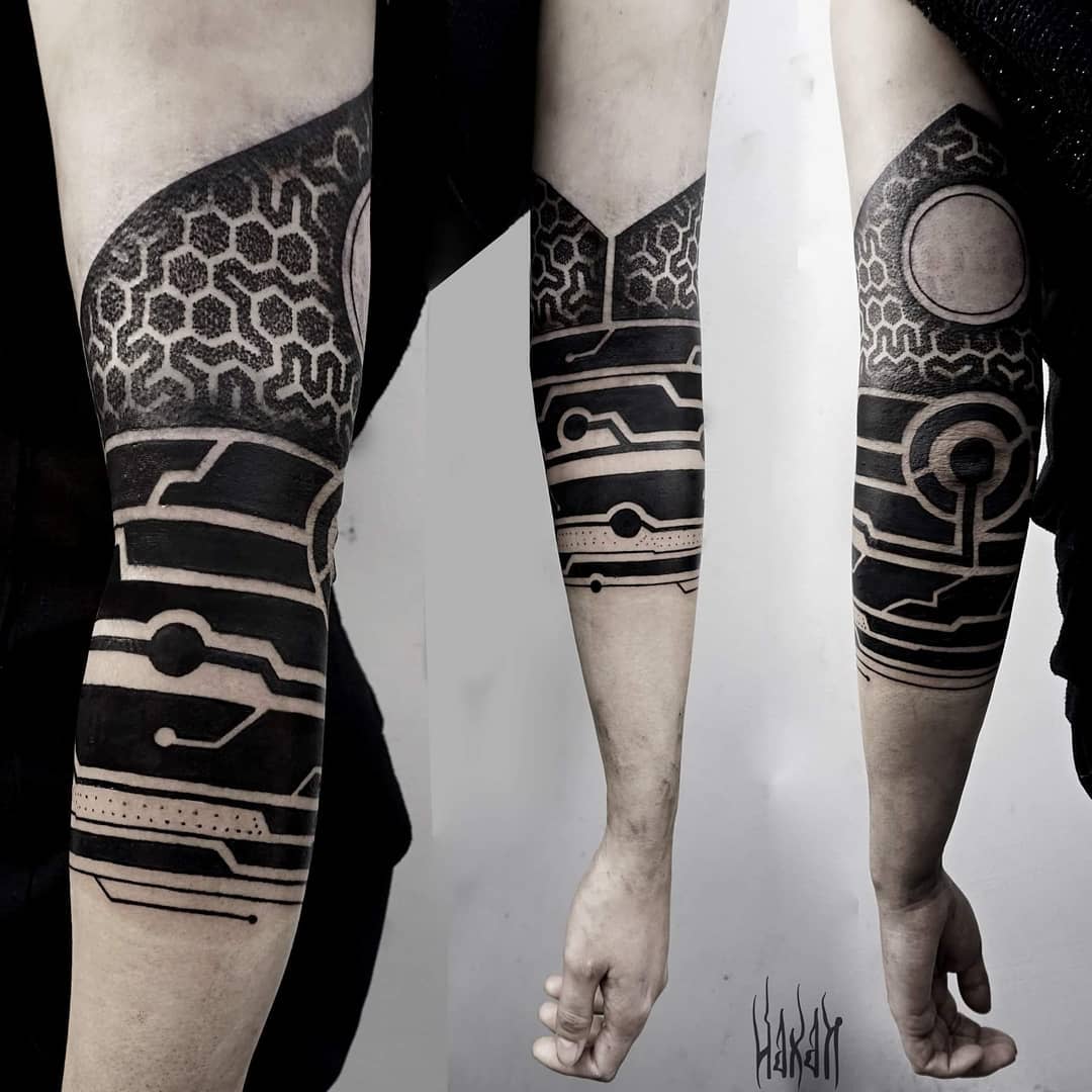 Bold cyberpunk tattoo on forearm featuring geometric and circuit patterns with heavy black ink